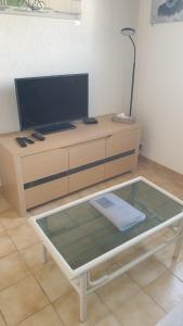 a glass table with a tv on top of a cabinet at Maison de vacances à louer À 200m de la plage ! in Dolus d'Oléron