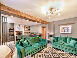 a living room with two green couches and a kitchen at Verona House in Tideswell