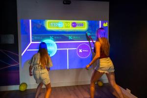two girls are playing a video game on a screen at Résidence Valkenburg in Valkenburg