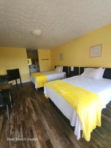 two beds in a hotel room with yellow walls at Fox Mountain Inn in Max Meadows