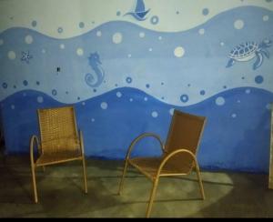 two chairs in front of a wall with a mural at Cantinho da Flor in Barretos