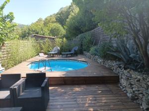 a small swimming pool on a wooden deck with chairs around it at l'Oppidum in Châteauneuf-du-Rhône