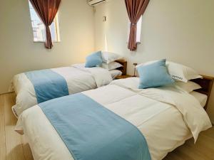 two beds in a room with blue and white at 大阪りんくん新築Yutori蘭 in Izumi-Sano
