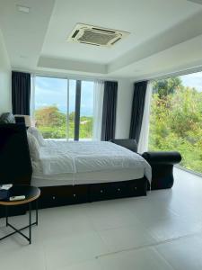 een slaapkamer met een groot bed en een groot raam bij modern hillside home in Ban Ko Khwan
