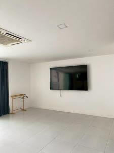 een kamer met een flatscreen-tv op een witte muur bij modern hillside home in Ban Ko Khwan