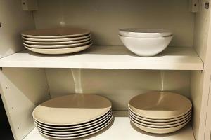 three plates and bowls on a shelf in a kitchen at Cozy 1-Bedroom in Central Oullins Steps from the Metro in Oullins