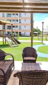 eine Terrasse mit Korbstühlen und ein Park mit einem Gebäude in der Unterkunft Muro Alto Condomínio Clube - Porto de Galinhas in Porto De Galinhas