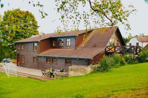 a house with two people sitting on a bench in front of it at Weavers' Guest House Kalndaki in Milzkalne