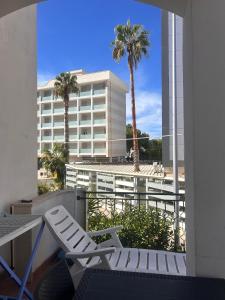 a balcony with a chair and a building with palm trees at Pearl Apartment - Baia Verde in Baia Verde