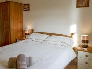a bedroom with a large white bed with two lamps at Nightingale Cottage- 25115 in Flamborough