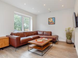 a living room with a brown leather couch and a table at Strathclaggan in Aberlour