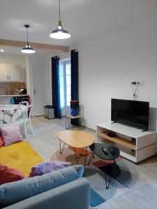 a living room with a couch and a tv at Gite de la Mouline in Lectoure