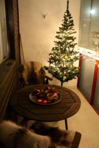 ロヴァニエミにあるA cozy Scandinavian condo in the city centerのクリスマスツリーのあるテーブルの隣に座っている犬
