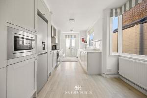 cocina con paredes blancas, suelo de madera y ventanas en New! Modern 4BR Home in Windsor City Centre - Sleeps 6 - Office & Garden, en Windsor