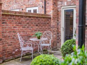 a patio with a table and chairs and a brick wall at The Lodge in York
