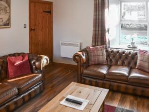 a living room with two leather couches and a coffee table at Mill Cottage in Belford