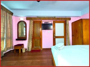 ナイニタールにあるHotel R - Radha - Continental -Mall Road Nainital - Near Naini Lake with Restaurant - Wifi - with Excellent Hospitality - A Luxury Room With Newly Decorated and Renovated Room- Book Nowのピンクの壁のベッドルーム(ベッド1台、テレビ付)