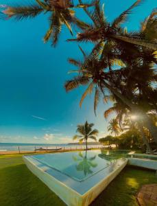 a swimming pool next to a beach with palm trees at El Sitio de Playa Venao in Playa Venao