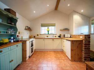 eine Küche mit weißen Schränken und einem Fliesenboden in der Unterkunft Brimble Cottage in Axminster