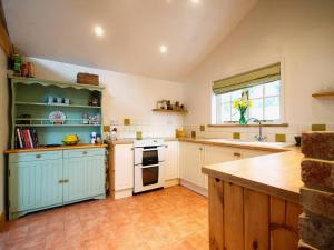 eine große Küche mit blauen Schränken und einem Waschbecken in der Unterkunft Brimble Cottage in Axminster