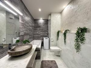 a bathroom with a large stone sink and a toilet at Simcity 3 I Skyline Elegance I 3BR, private parking, sunny terrace with panoramic city view 5min walk to city square in Banská Bystrica