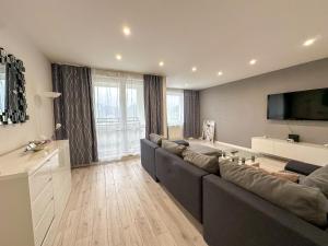 a living room with a large couch and a flat screen tv at Simcity 3 I Skyline Elegance I 3BR, private parking, sunny terrace with panoramic city view 5min walk to city square in Banská Bystrica