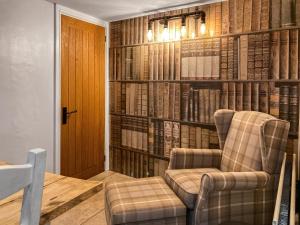 a living room with a chair and a book wall at Cosy Cottage in Portinscale
