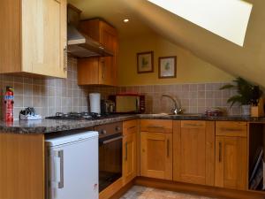 a kitchen with wooden cabinets and a white dishwasher at Fennel Folly - Uk32608 in Manton