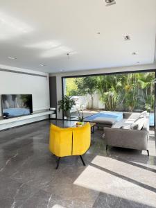 a living room with a yellow chair and a couch at Villa with a pool in Ra'anana in Ra‘ananna