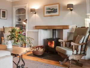 sala de estar con estufa de leña y mesa en Strathcashel Cottage, en Rowardennan