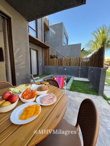 a wooden table with plates of food on it at MHV Milagres - Casa Maria, Refugio em condomínio a poucos metros da paradisíaca praia do Marceneiro! in Passo de Camarajibe