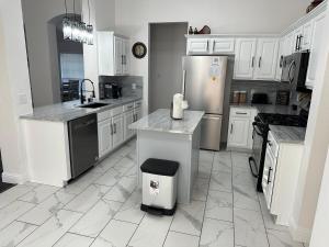 Una cocina con gabinetes blancos y electrodomésticos de acero inoxidable. en 3 Bedroom House, en Frisco