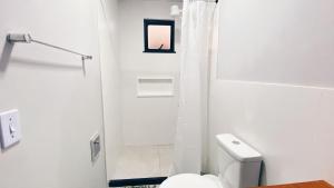 une salle de bain blanche avec toilettes et douche dans l'établissement Pousada Atalaia - Arraial do Cabo, à Arraial do Cabo