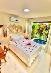a bedroom with a white bed with red hearts on it at BANGATACHO - Bangalôs Temáticos com Experiências Românticas Exclusivas - Praia do Patacho in Pôrto de Pedras