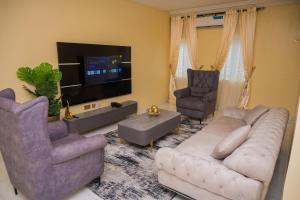 a living room with a couch and two chairs and a tv at Jasabi s Court Apartments in Port Harcourt