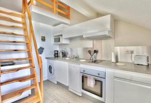 a small kitchen with white cabinets and a ladder at Studio Sable Cannelle in Le Gosier