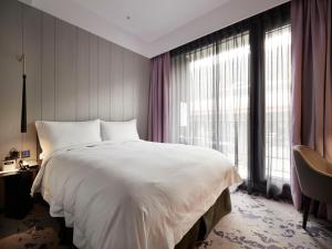 a bedroom with a large white bed and a large window at Tango Inn Taipei Jihe in Taipei