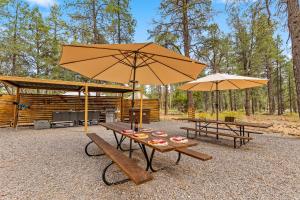 a picnic table with two benches and an umbrella at Highland Grand Canyon Glamping in Grand Canyon Village +14 photos