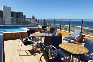a balcony with tables and chairs and a swimming pool at Para quem deseja conforto e bem estar in Salvador