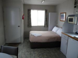 a hotel room with a bed and a refrigerator at Wodonga Caravan & Cabin Park in Wodonga