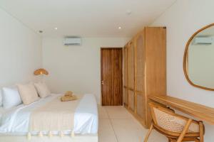 a white bedroom with a bed and a mirror at Modern 3BR Villa, Rooftop Dining and Fast WiFi in Pererenan