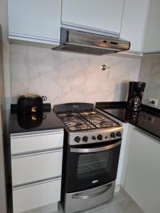 a kitchen with a stove top oven and white cabinets at Quinta Luna 10 - Playa Bonita in San Carlos de Bariloche