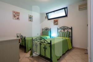 2 grüne Betten in einem Zimmer mit Fenster in der Unterkunft Homiday - Green Bay Village in Pineto