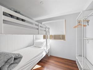 ein weißes Schlafzimmer mit 2 Etagenbetten und einem Spiegel in der Unterkunft Leeuwin Cottage in Augusta