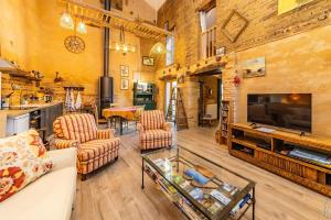 Una sala de estar con un sofá y sillas y un televisor. en Duplex des Vignes - Nature - Montans, en Montans