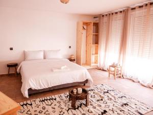 a bedroom with a white bed and a large window at Berber Shelter in Tamraght Ouzdar