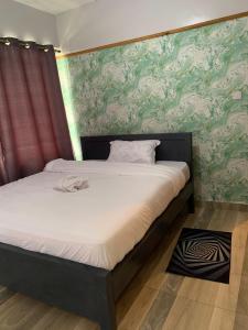 Bett in einem Schlafzimmer mit grüner und weißer Tapete in der Unterkunft Bnb in Thuthuriki