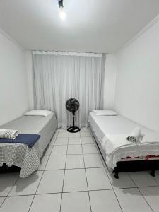 a bedroom with two beds and a fan in it at Apartamento Central 2 quartos e 2 banheiros, perto shopping in Juazeiro