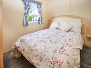 a bedroom with a bed with a floral comforter and a window at J And M Retreat in Morecambe