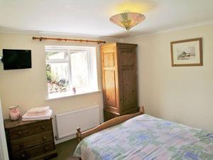 ein Schlafzimmer mit einem Bett, einer Kommode und einem Fenster in der Unterkunft Chapel Cottage in Kentisbury